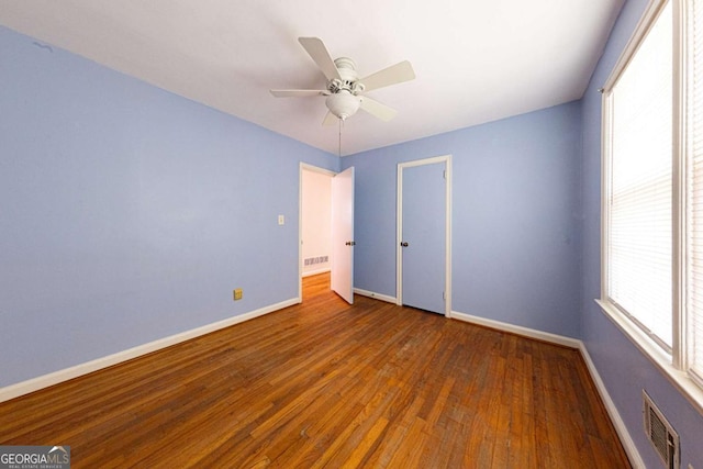 unfurnished bedroom featuring ceiling fan, visible vents, baseboards, and wood finished floors