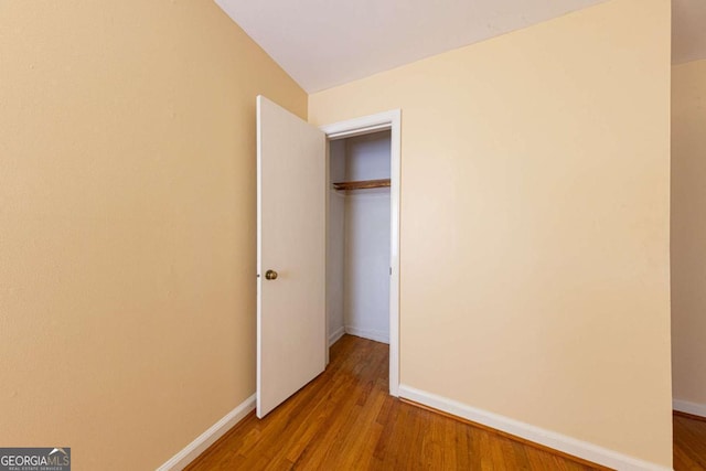 unfurnished bedroom featuring a closet, baseboards, and wood finished floors