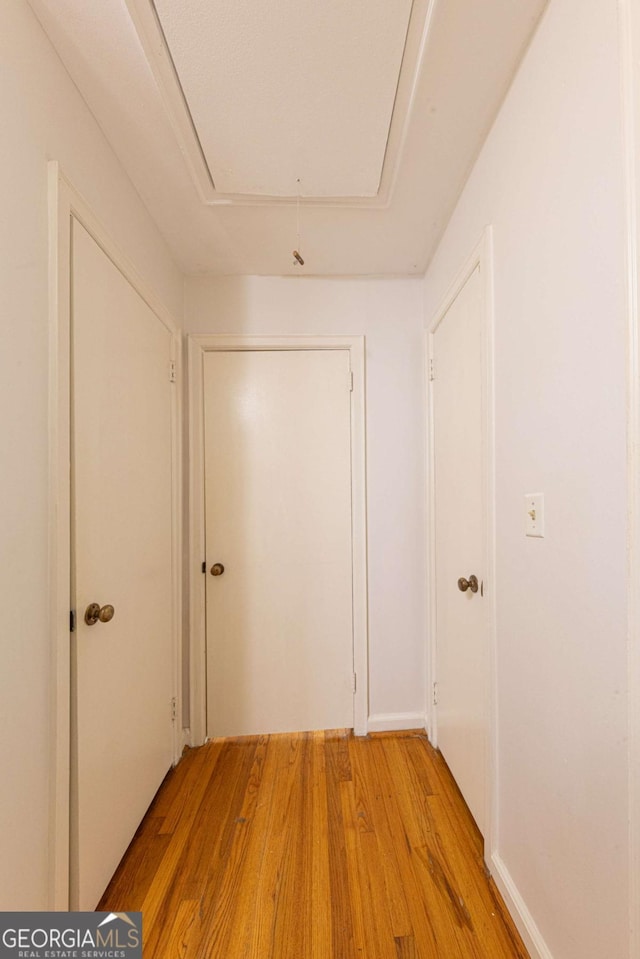 hall with light wood-type flooring and attic access