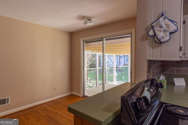kitchen featuring tasteful backsplash, light wood-type flooring, visible vents, and baseboards