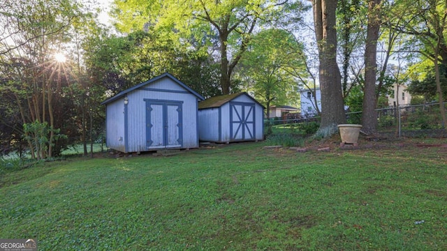view of yard featuring an outdoor structure, fence, and a storage unit