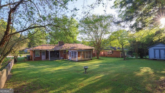 view of yard with an outbuilding, a fenced backyard, a sunroom, and a storage unit