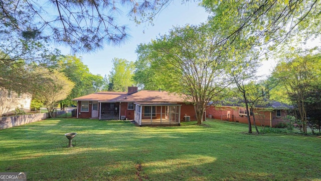 rear view of house with fence, a chimney, and a lawn