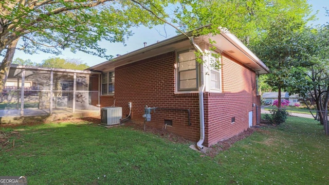 view of home's exterior featuring a sunroom, a yard, fence, cooling unit, and brick siding