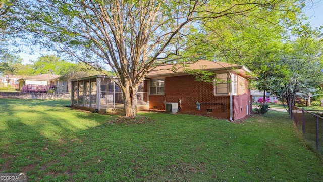 rear view of house with brick siding, fence, a yard, and a sunroom