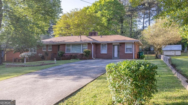 ranch-style house with driveway, fence, a front lawn, and brick siding