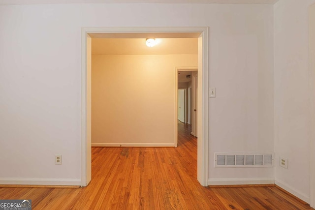 empty room featuring visible vents, baseboards, and wood finished floors