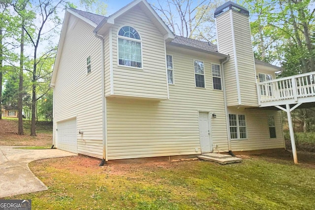 28 Willow Ridge Dr, Hampton, GA 30228 - back of property with concrete driveway, a deck, a chimney, and an attached garage