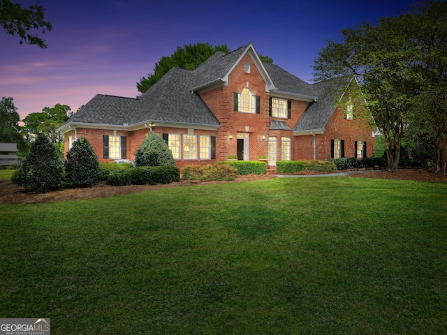 traditional-style home featuring a front yard, brick siding, and a shingled roof