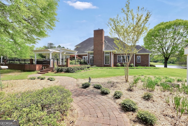 rear view of house with brick siding, a chimney, a pergola, and a lawn