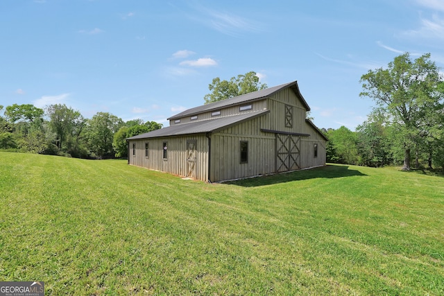 rear view of house with an outbuilding, metal roof, a barn, and a lawn