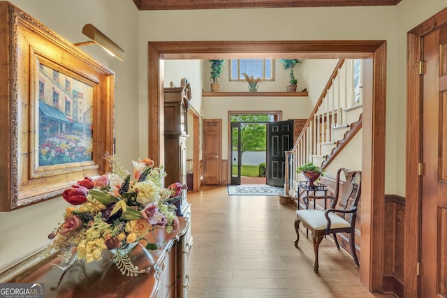 entrance foyer with ornamental molding, stairway, and wood finished floors