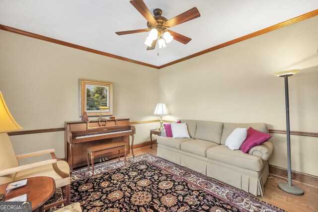 living room with wood finished floors, ornamental molding, baseboards, and a ceiling fan