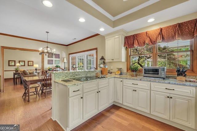 kitchen with a notable chandelier, ornamental molding, a toaster, light stone countertops, and black electric cooktop