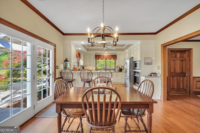 dining space featuring light wood-type flooring, an inviting chandelier, and ornamental molding