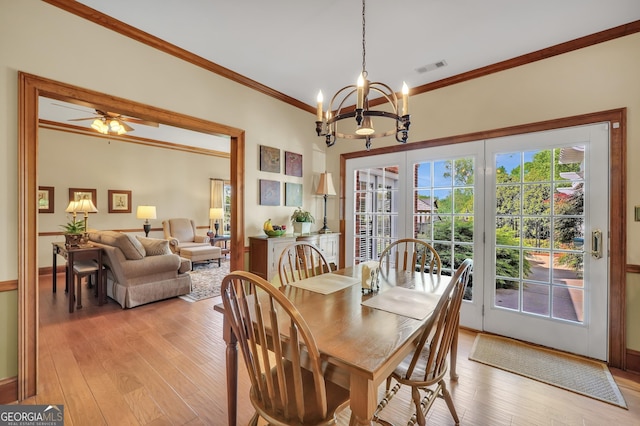 dining space featuring ornamental molding, visible vents, light wood-type flooring, and ceiling fan with notable chandelier