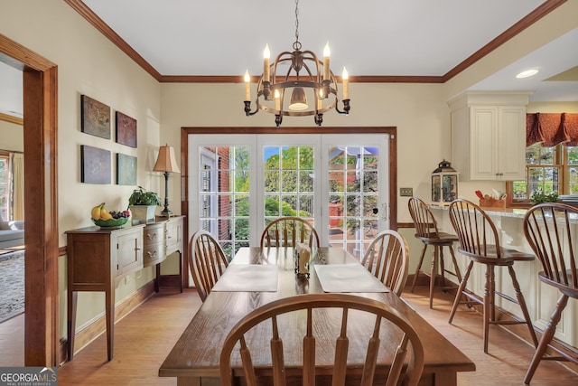 dining area featuring ornamental molding, light wood-style flooring, a notable chandelier, and baseboards