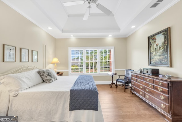 bedroom featuring visible vents, crown molding, a tray ceiling, recessed lighting, and light wood-style flooring