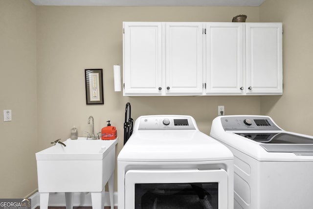 clothes washing area featuring washing machine and clothes dryer, a sink, and cabinet space