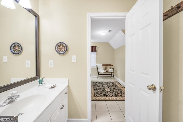 bathroom with visible vents, baseboards, vanity, vaulted ceiling, and tile patterned flooring