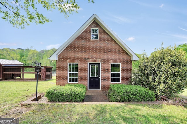 back of house with an outbuilding, a yard, and brick siding