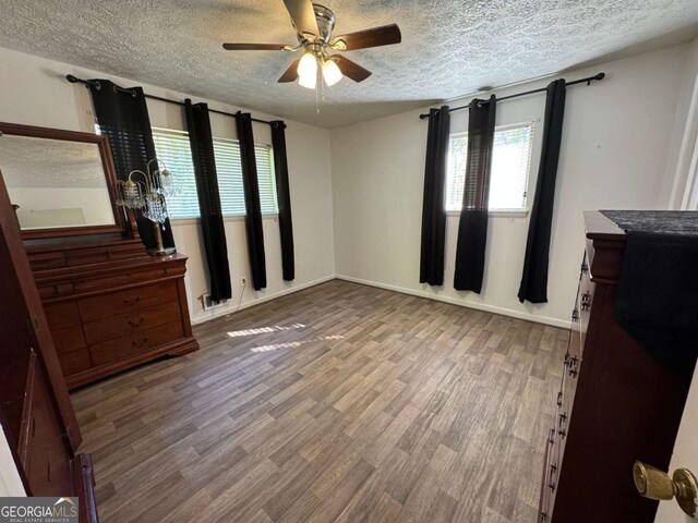 6695 Cedar Hurst Trl, Atlanta, GA 30349 - unfurnished bedroom featuring ceiling fan, baseboards, wood finished floors, and a textured ceiling