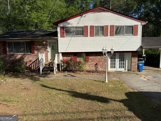 6695 Cedar Hurst Trl, Atlanta, GA 30349 - split level home featuring a carport, french doors, driveway, a front lawn, and brick siding