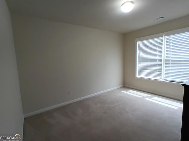 carpeted spare room featuring baseboards and visible vents