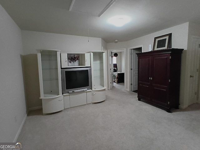 unfurnished living room with attic access, baseboards, and carpet floors