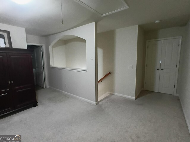 spare room featuring light carpet and baseboards