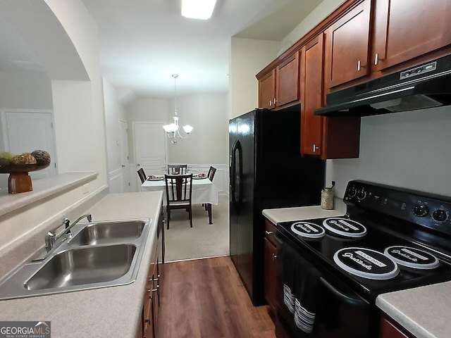 kitchen with dark wood-type flooring, under cabinet range hood, a sink, light countertops, and black / electric stove
