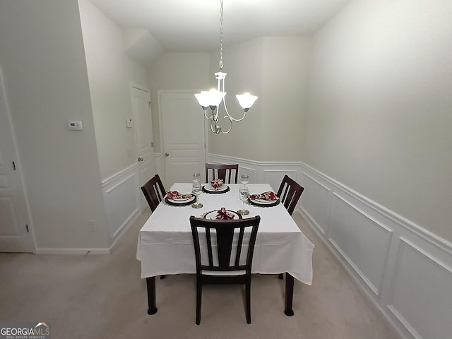 carpeted dining space featuring a chandelier, a decorative wall, and wainscoting
