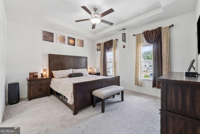 bedroom featuring light colored carpet, baseboards, visible vents, and a raised ceiling