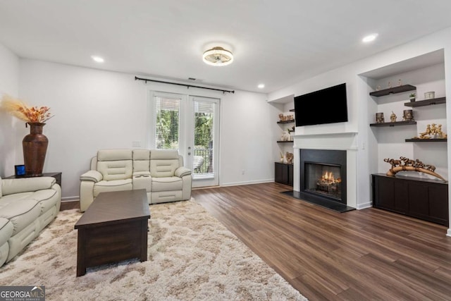 living area featuring a lit fireplace, wood finished floors, baseboards, and recessed lighting