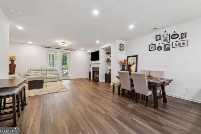 dining area featuring recessed lighting, a fireplace with flush hearth, baseboards, and wood finished floors