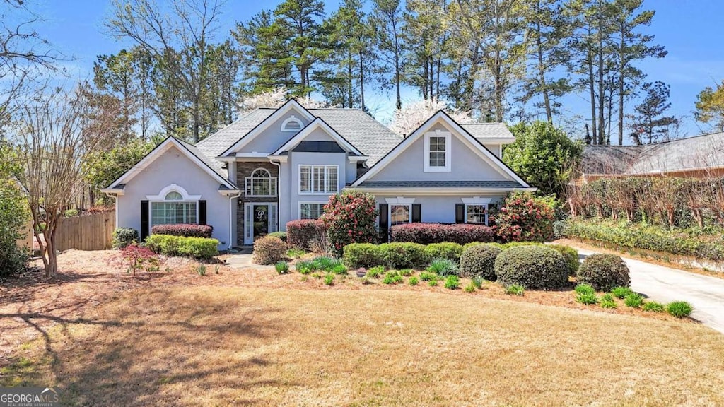 view of front facade with a front yard, fence, and stucco siding
