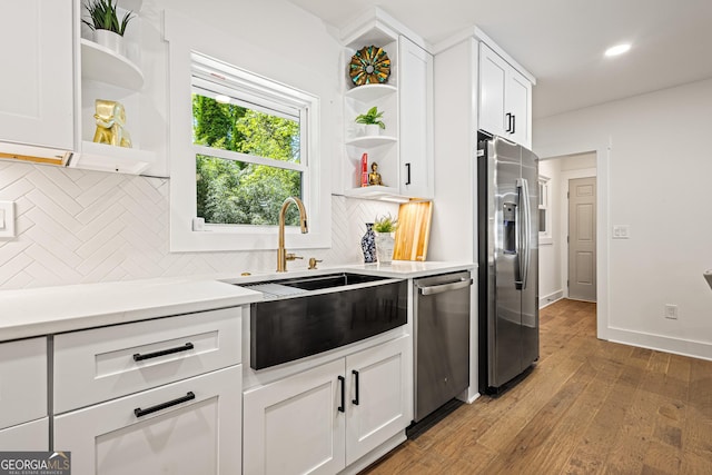 kitchen with open shelves, a sink, decorative backsplash, light wood-style flooring, and appliances with stainless steel finishes