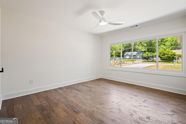 unfurnished room featuring visible vents, baseboards, dark wood-style floors, and ceiling fan