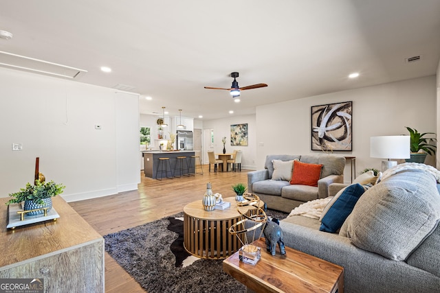 living room featuring attic access, light wood-style floors, ceiling fan, and recessed lighting