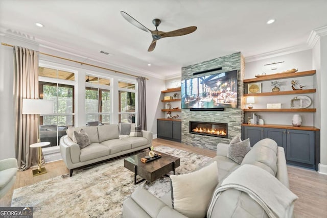 living room featuring light wood-type flooring, visible vents, ornamental molding, and a ceiling fan