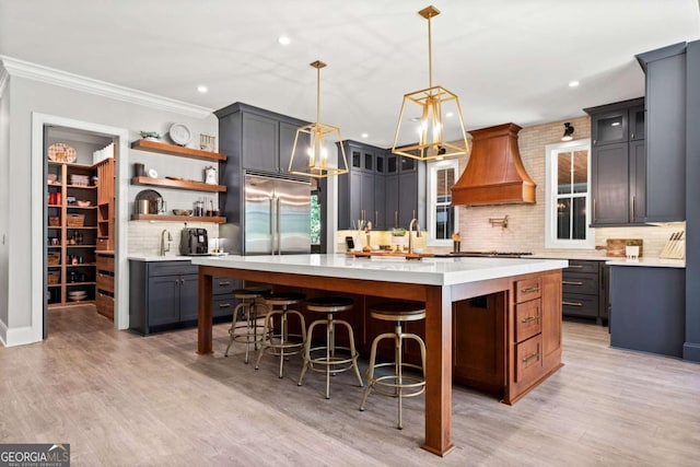 kitchen featuring tasteful backsplash, appliances with stainless steel finishes, light countertops, premium range hood, and recessed lighting