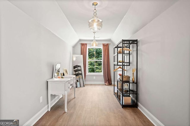corridor featuring lofted ceiling, wood finished floors, and baseboards