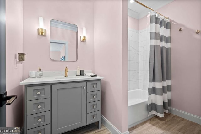 bathroom featuring wood finished floors, vanity, shower / bath combination with curtain, and baseboards