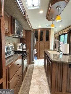 kitchen featuring pendant lighting, a kitchen island with sink, a sink, stainless steel appliances, and a toaster