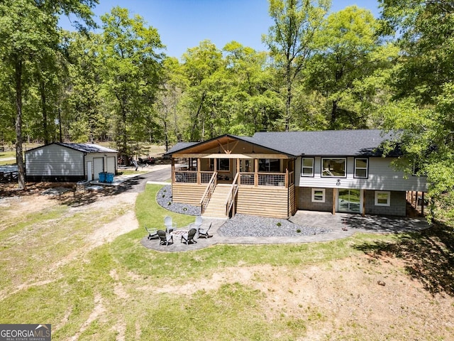 exterior space with roof with shingles, stairway, an outbuilding, a lawn, and covered porch