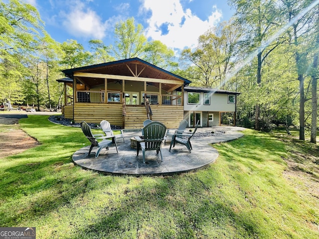 rear view of property with a yard, a patio, and a fire pit