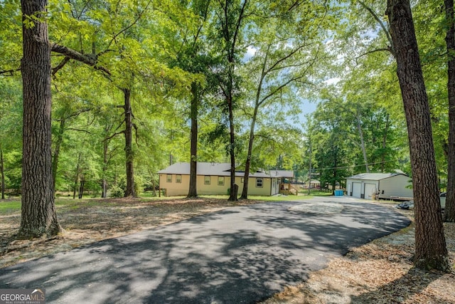 view of front facade with aphalt driveway, an outdoor structure, and a garage