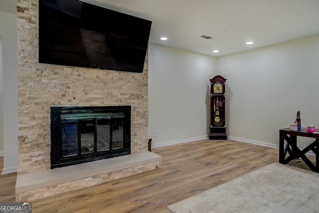 unfurnished living room featuring a fireplace, recessed lighting, baseboards, wood finished floors, and visible vents