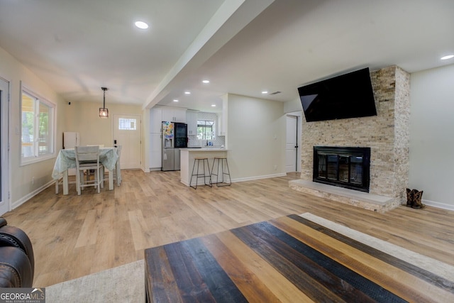 living area with baseboards, light wood finished floors, and a fireplace