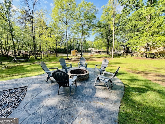 view of patio with a storage unit, an outbuilding, and a fire pit